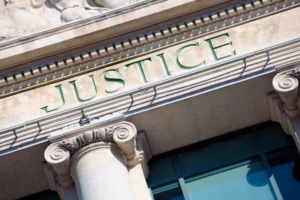 image with a frontend of a courthouse with the word "justice" on it